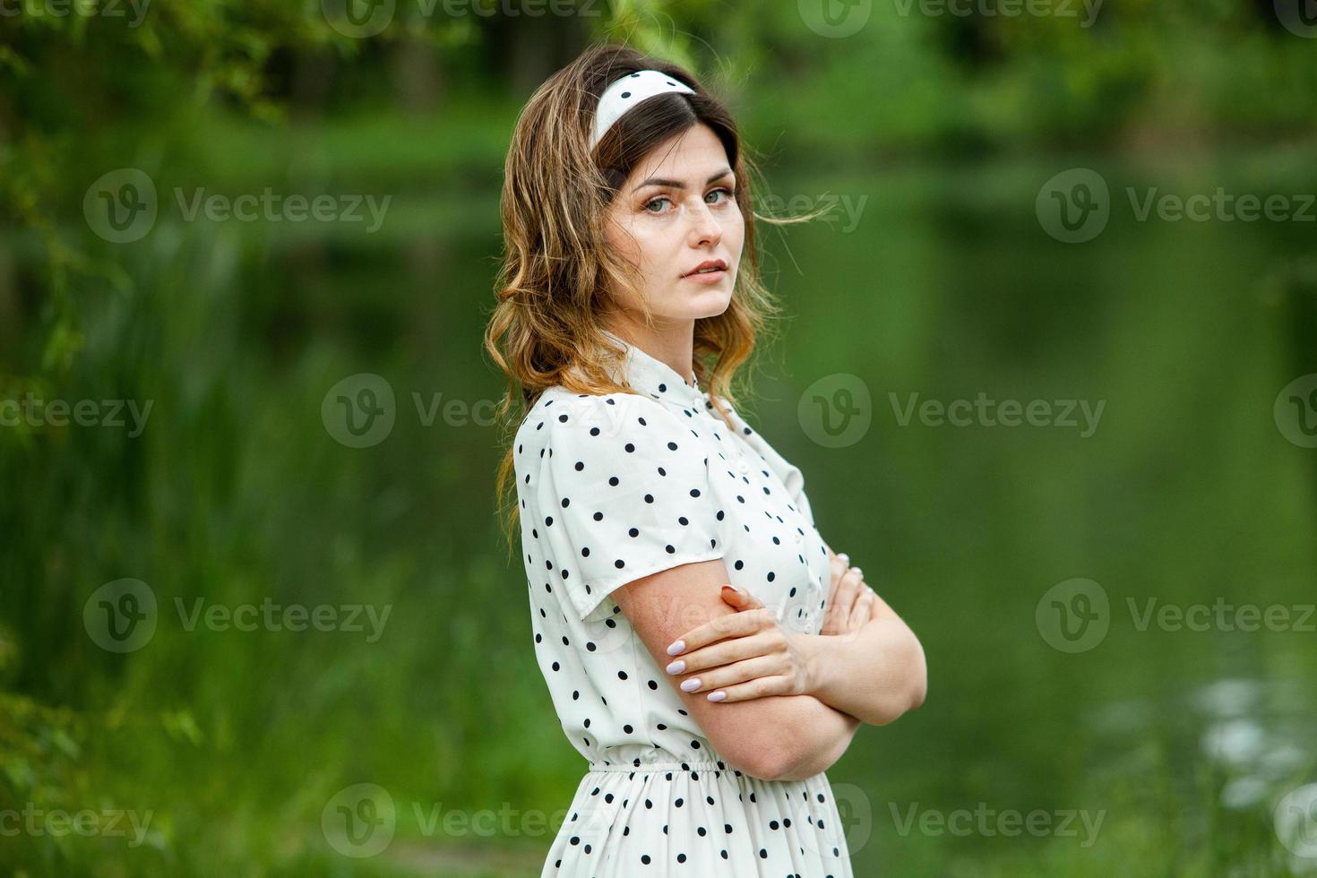Woman's portrait with a hair moving in the wind.  portrait of young beautiful Russian brunette girl at summer green park. European white woman in dress. photo