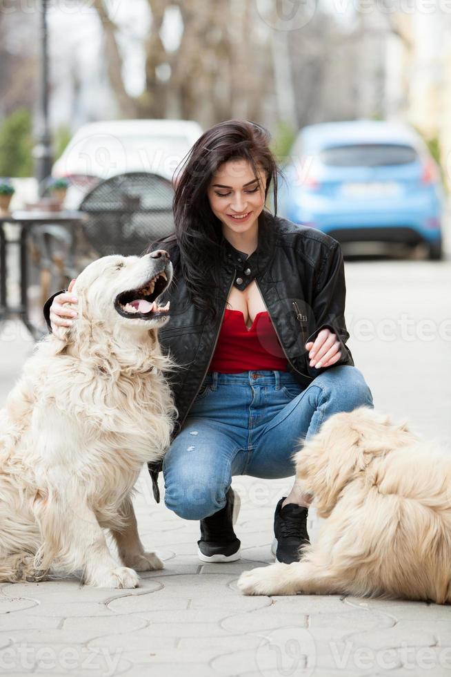 Girl walking in the city with his dogs. Woman playing with a white dog