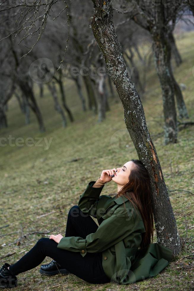 Image of young beautiful woman wearing rain jacket in cold weather. Thinker european girl in spring nature. photo