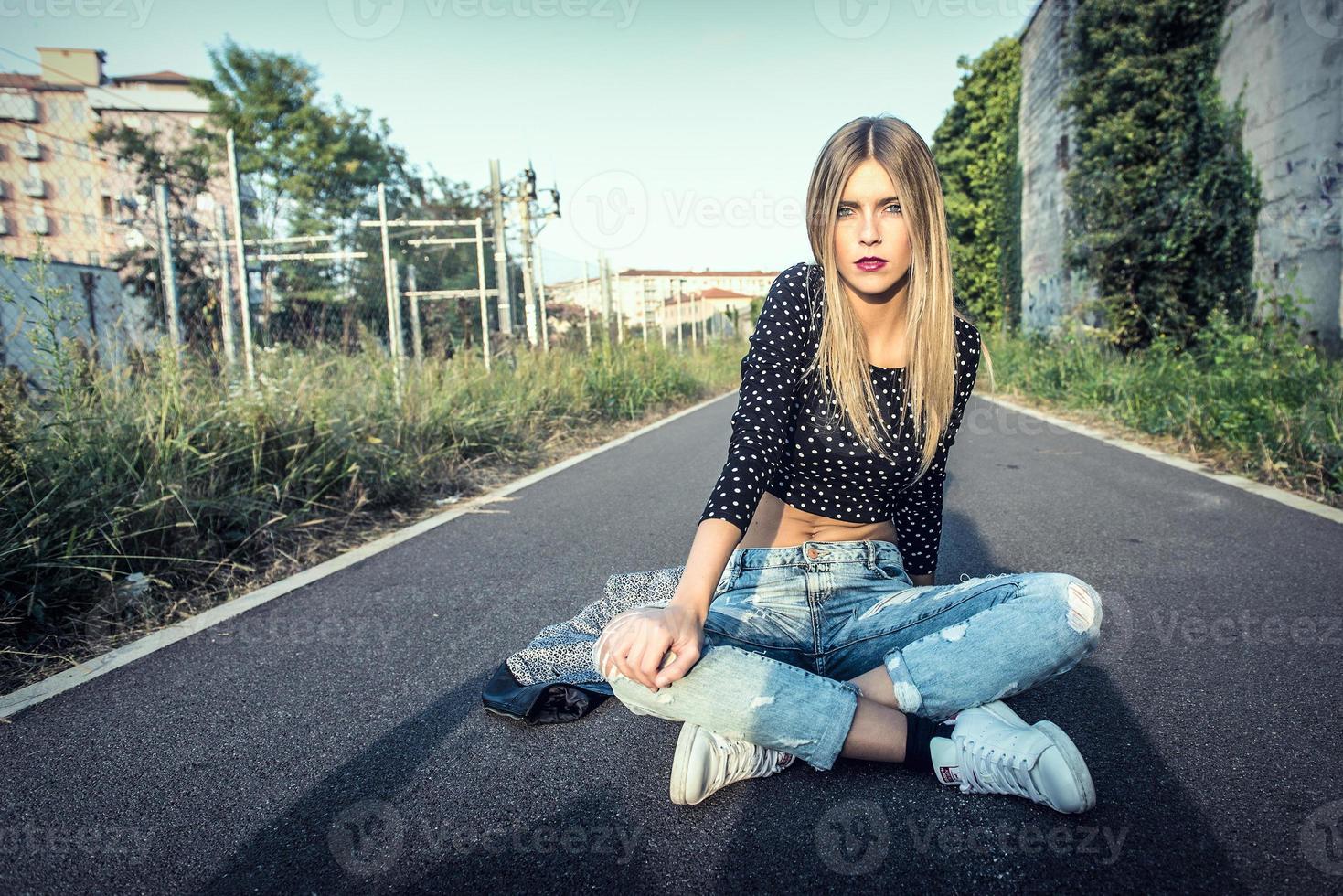 Beautiful blonde girl sitting on the street in town photo