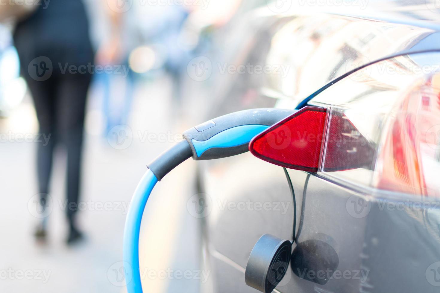 An electric car is charged with energy by a road dispenser photo