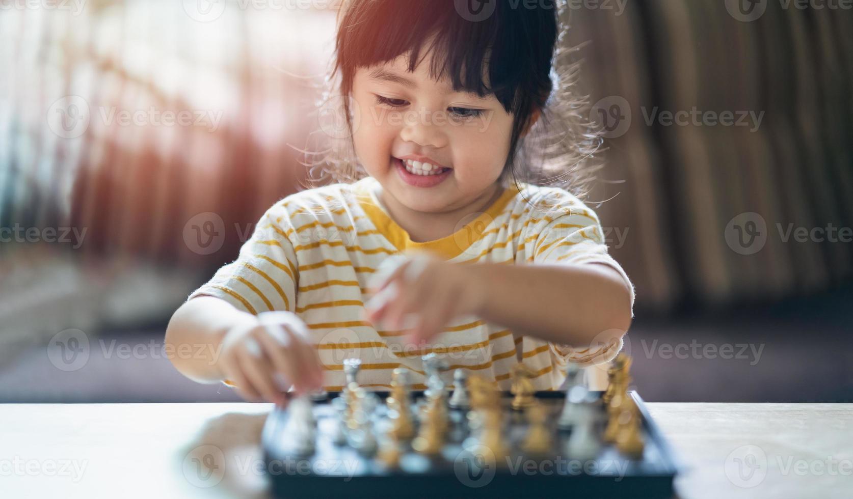 Little asian baby playing chess in the living room at home.Smart kid.fashion children. Little genius Child. Intelligent game.Chessboard. Baby activity concept. photo