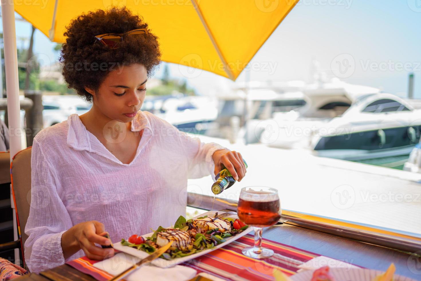 Black woman adding oil to dish in street restaurant photo