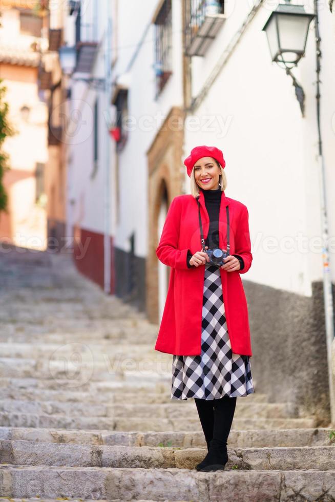 dama de moda sonriente de pie en las escaleras durante el turismo en la ciudad foto