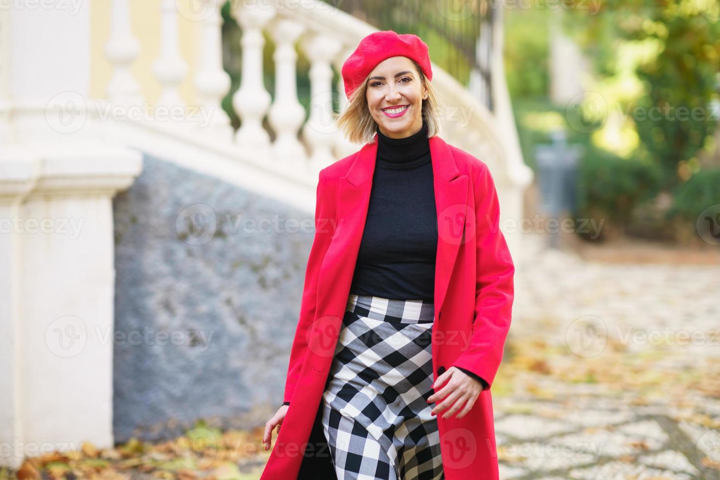 Smiling woman in stylish outfit walking on street photo