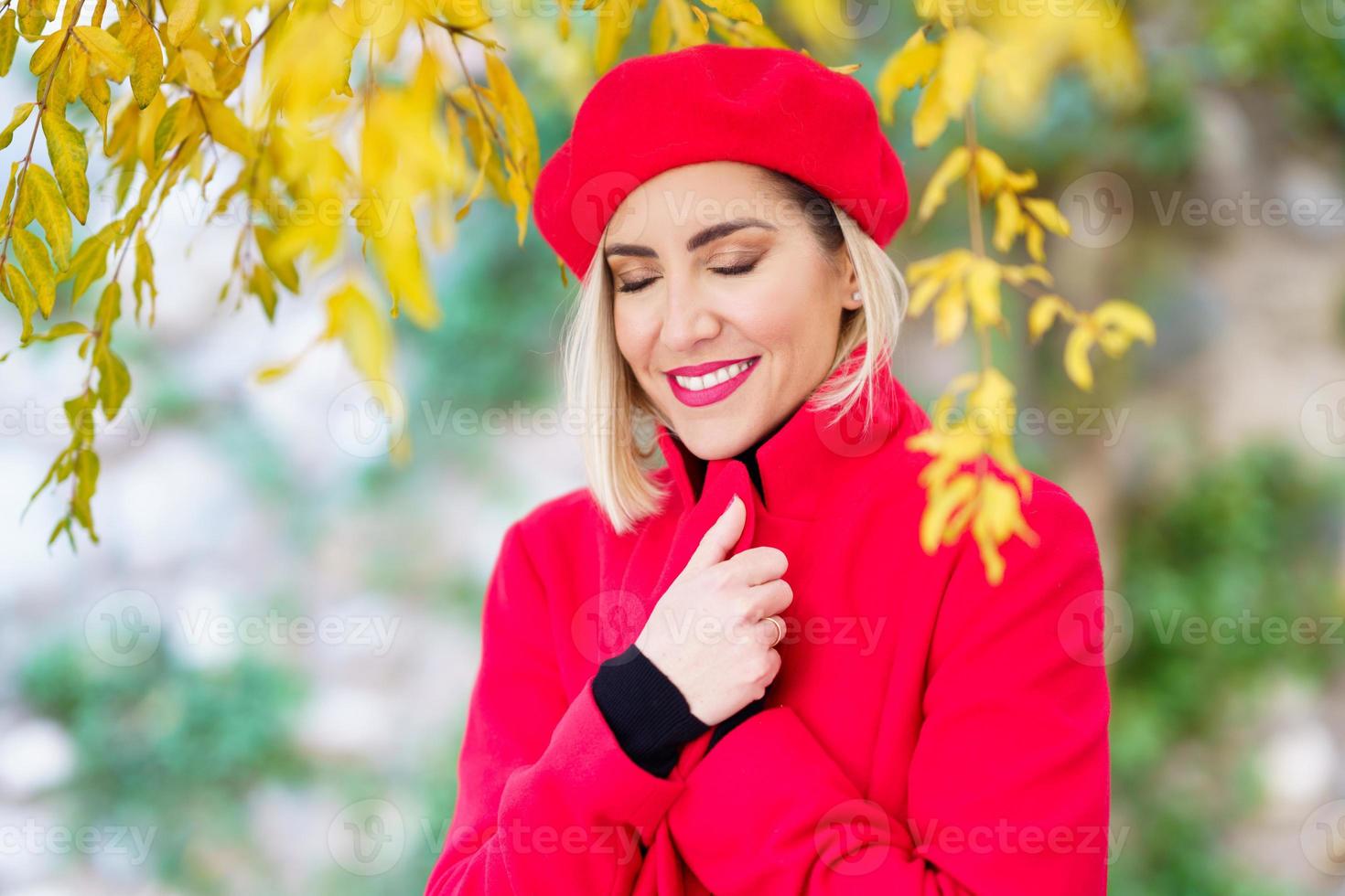 Happy gorgeous woman with closed eyes standing in autumn garden photo