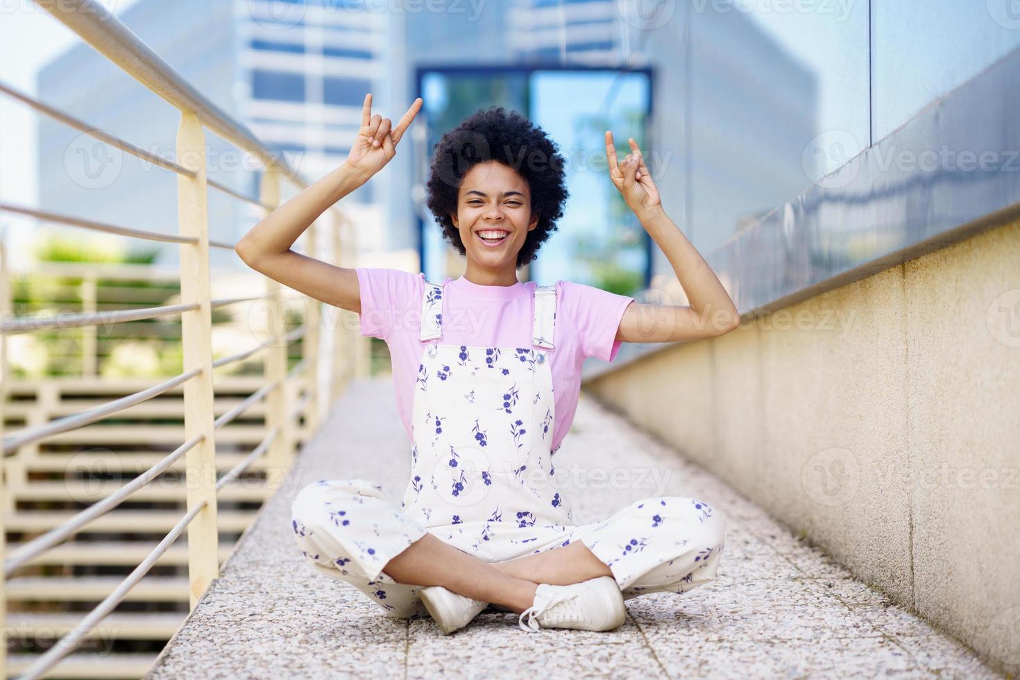 Smiling black woman showing horn signs photo