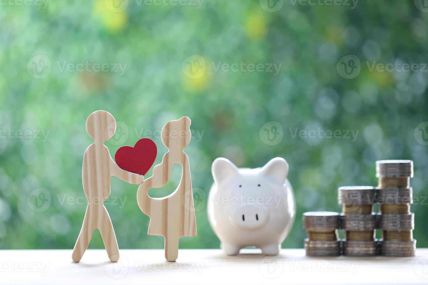 Love couple holding heart shape with piggy bank and stack of coins money on natural green background,Save money for prepare in future and family finance concept photo