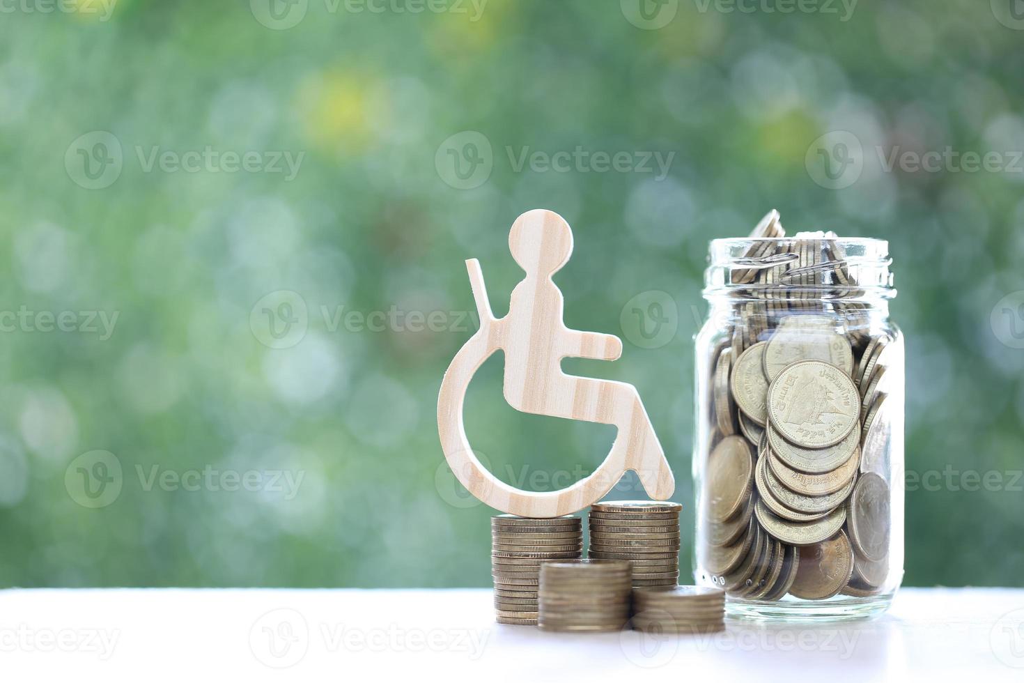 Man on wheelchair and gold coin money in the glass bottle on natural green background,Save money for prepare in future and handicapped person concept photo