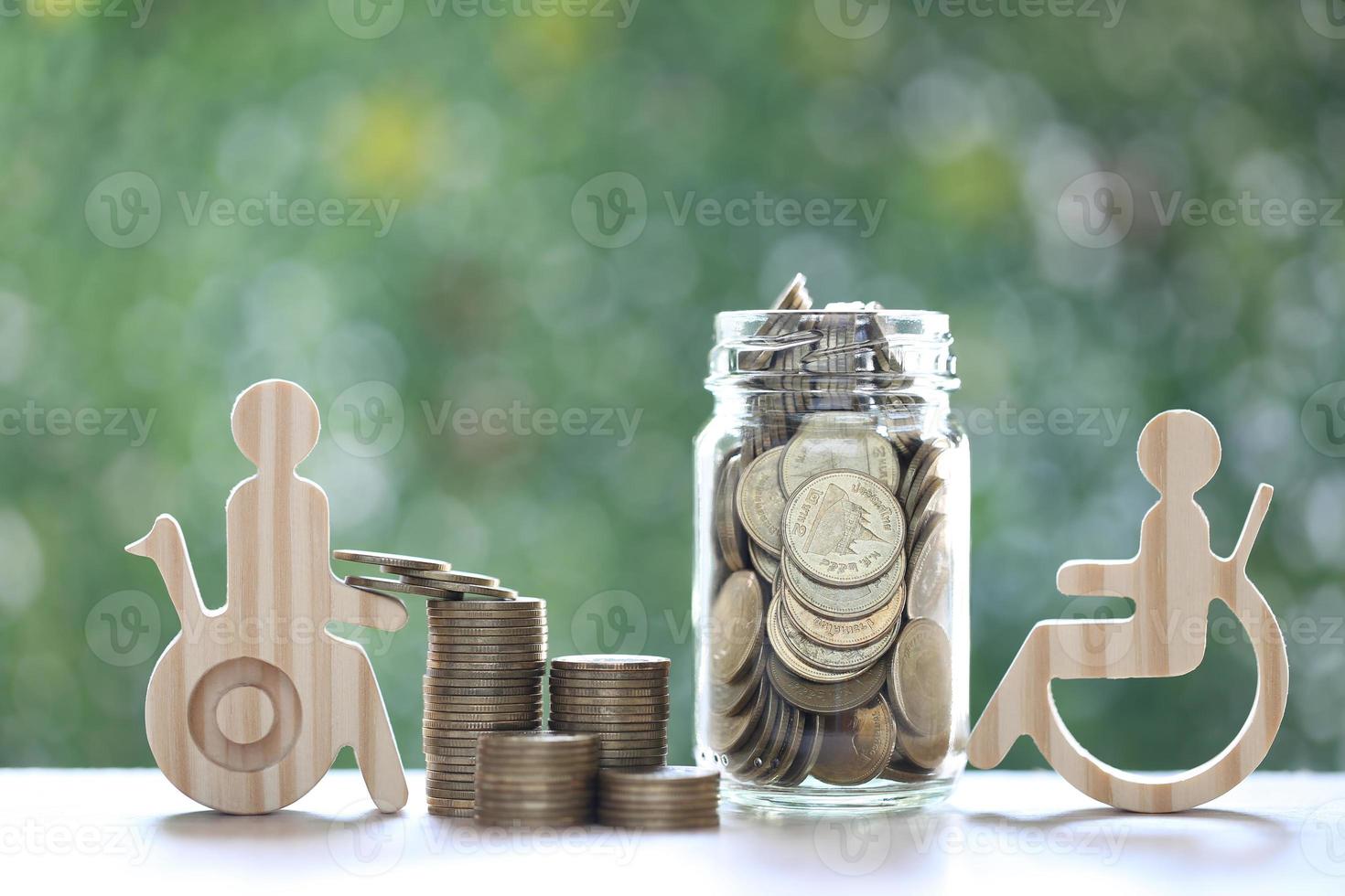 hombre en silla de ruedas y moneda de oro en la botella de vidrio sobre fondo verde natural, ahorre dinero para prepararse en el futuro y el concepto de persona discapacitada foto