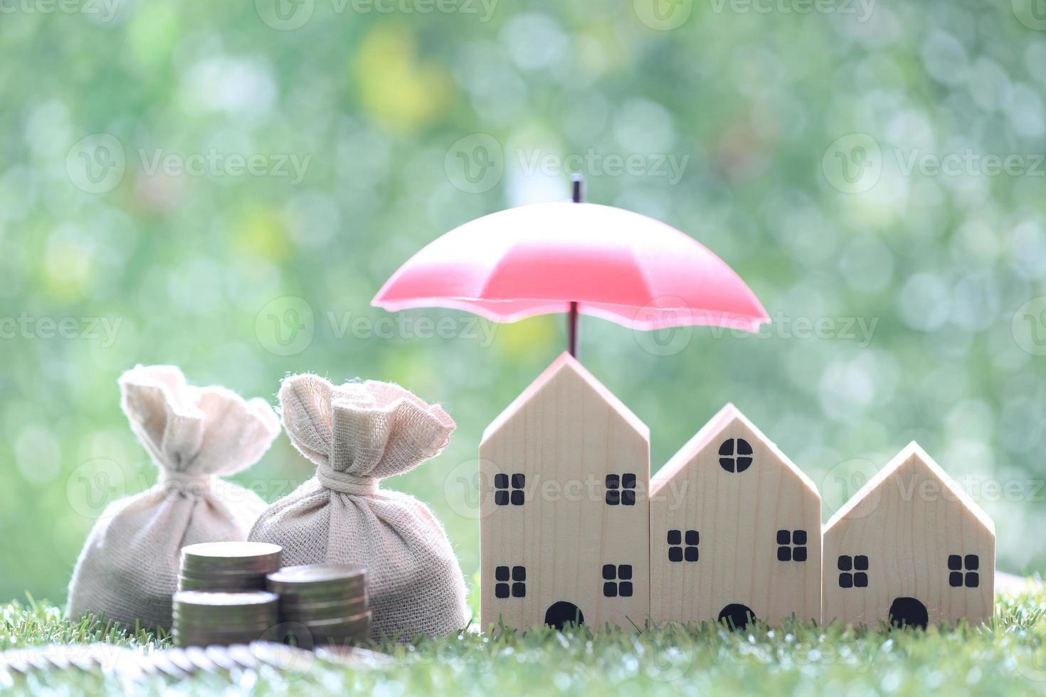 Protection, Coins money in the bag under the umbrella and model house on natural green background, Finance insurance and Safe investment concept photo