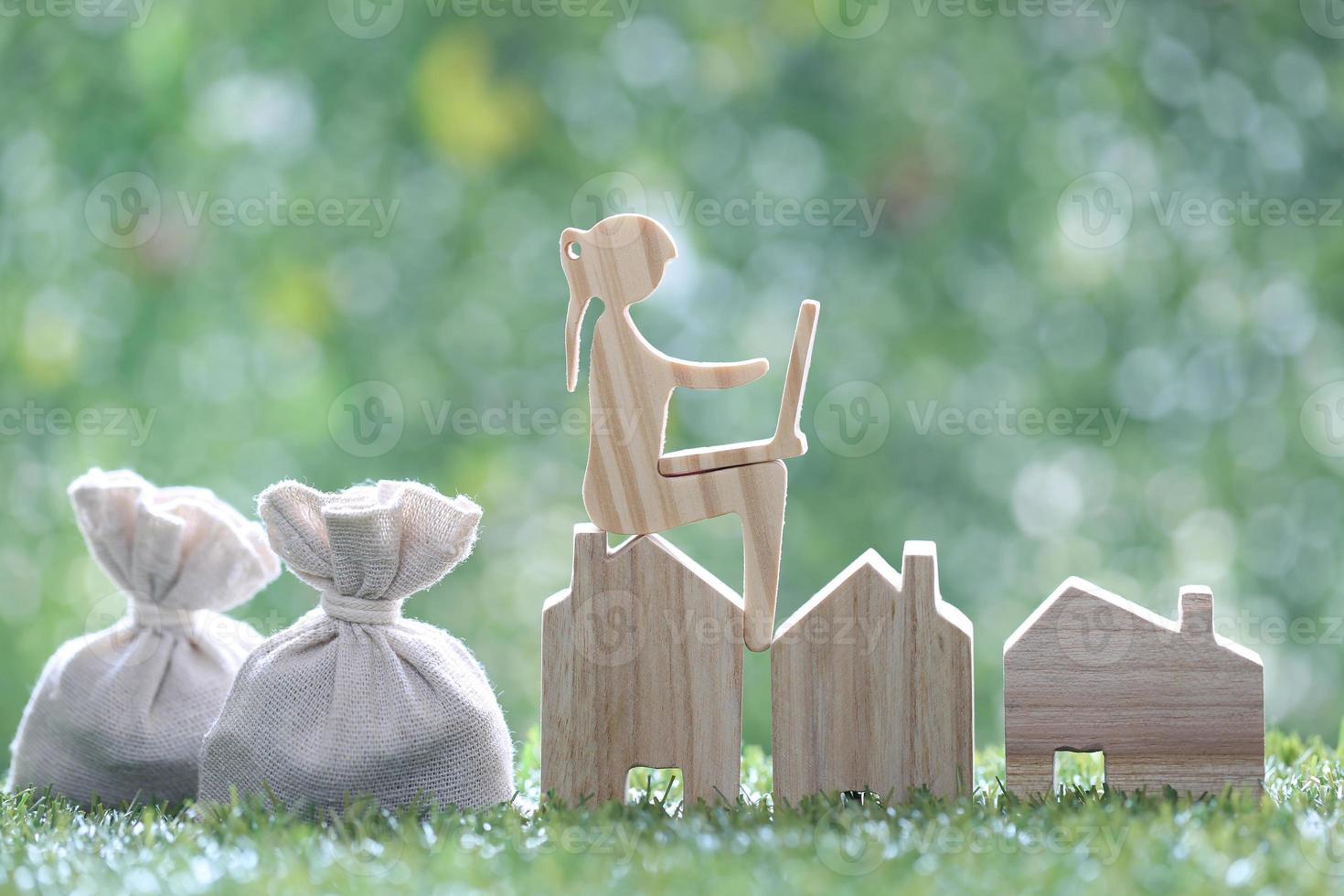 Investment and business concept,Woman using laptop computer and model house with money bag on natural green background,Investors strategy,Inflation photo
