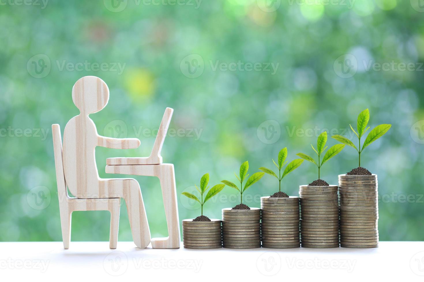 Investment and business concept,Man using laptop computer with trees growing on stack of coins money on natural green background,Investors strategy photo