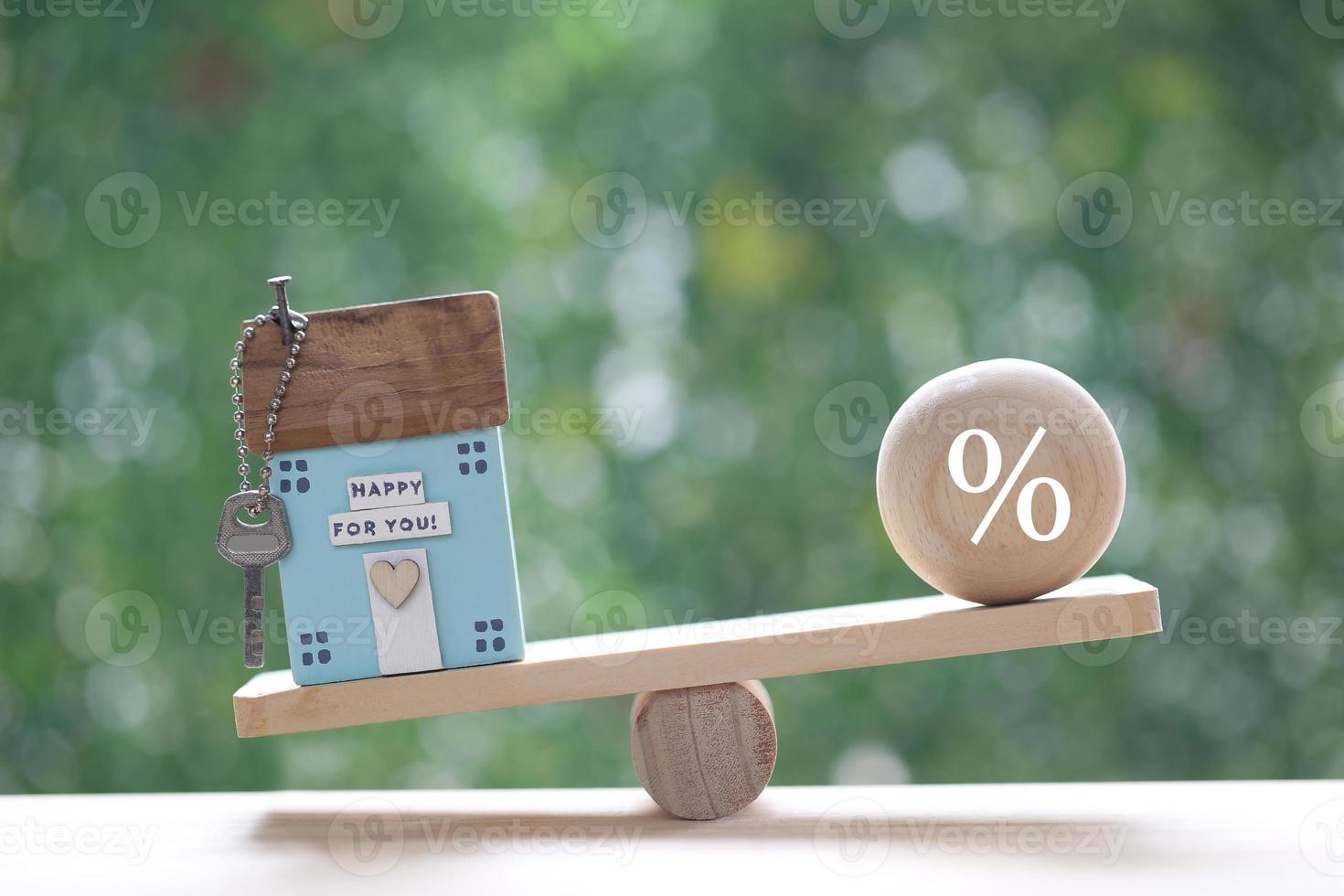 Interest rate up and Banking concept, Model house with percentage symbol icon on wood scale seesaw on natural green background, Business investment and real estate photo
