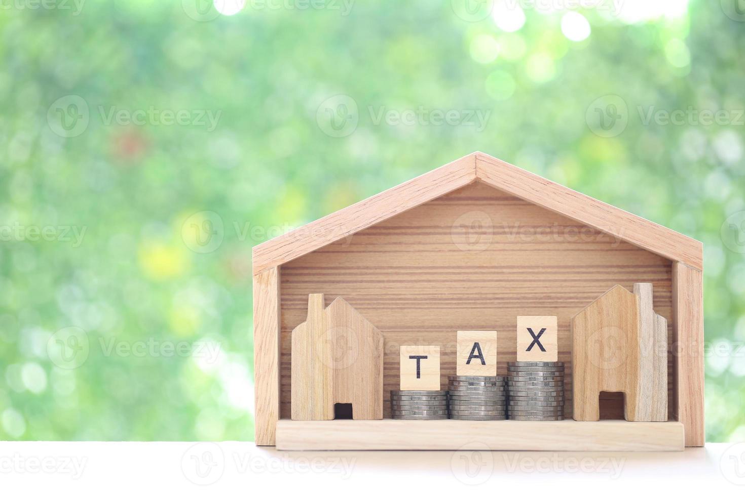 Estate tax,Model house with stack of coins money and tax word on green background,Business investment and Property tax concept photo