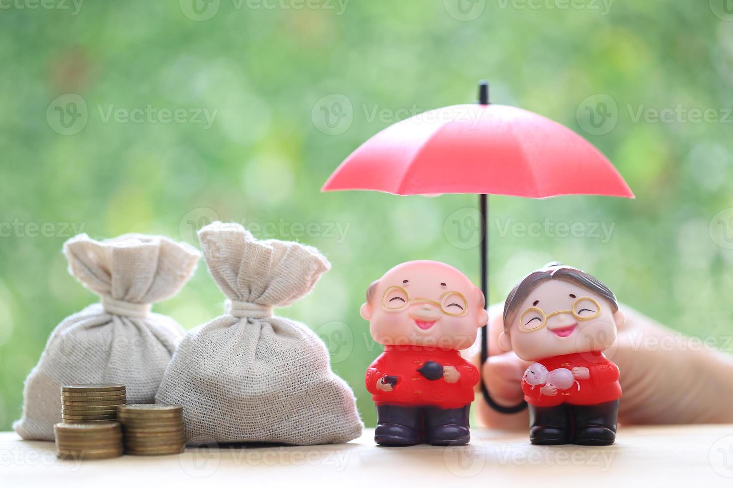 Mutual fund,Love couple senior and hand holding the umbrella with stack of coins money on natural green background, Save money for prepare in future and pension retirement concept photo