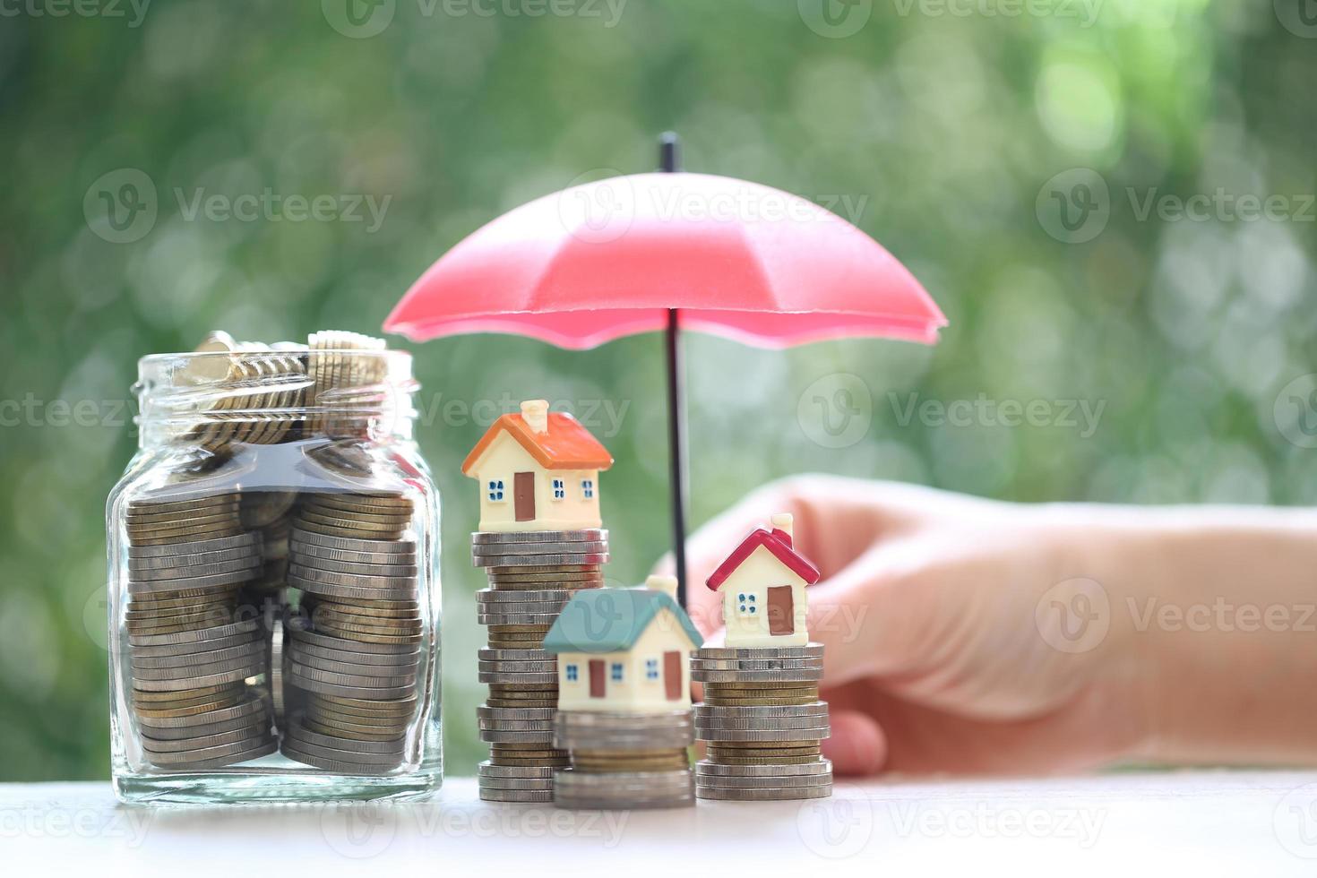 Protection, Model house on stack of coins money with the umbrella on nature green background,Finance insurance and Safe investment concept photo