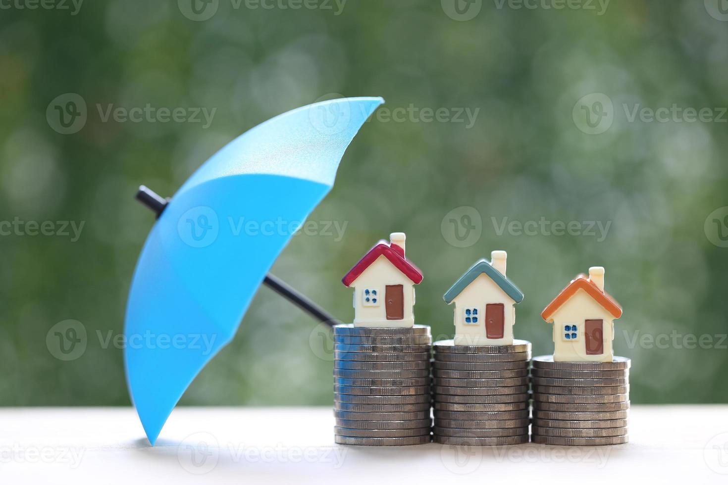 Protection, Model house on stack of coins money with the umbrella on nature green background,Finance insurance and Safe investment concept photo