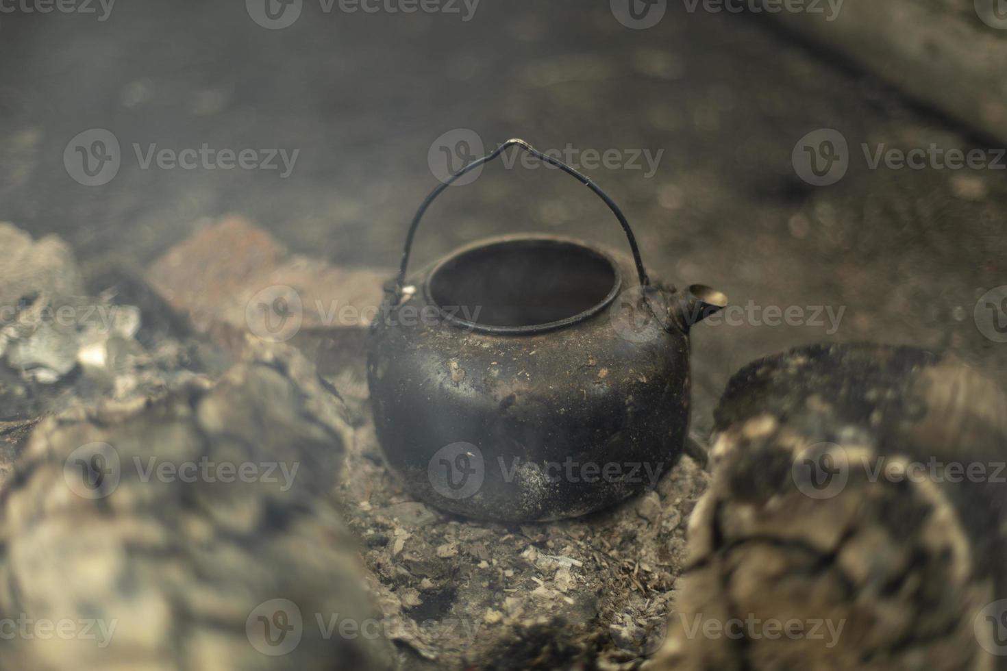 Kettle stands on coals. Kitchen in nature. Picnic details. photo