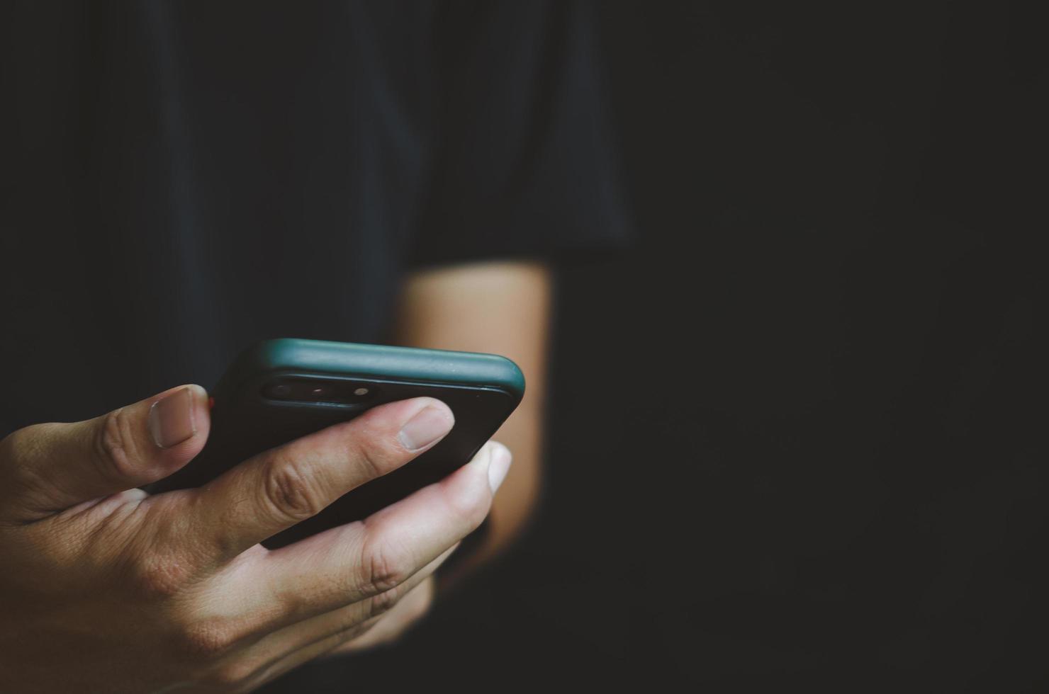 persona que sostiene en la mano el teléfono móvil aislado sobre fondo negro. foto