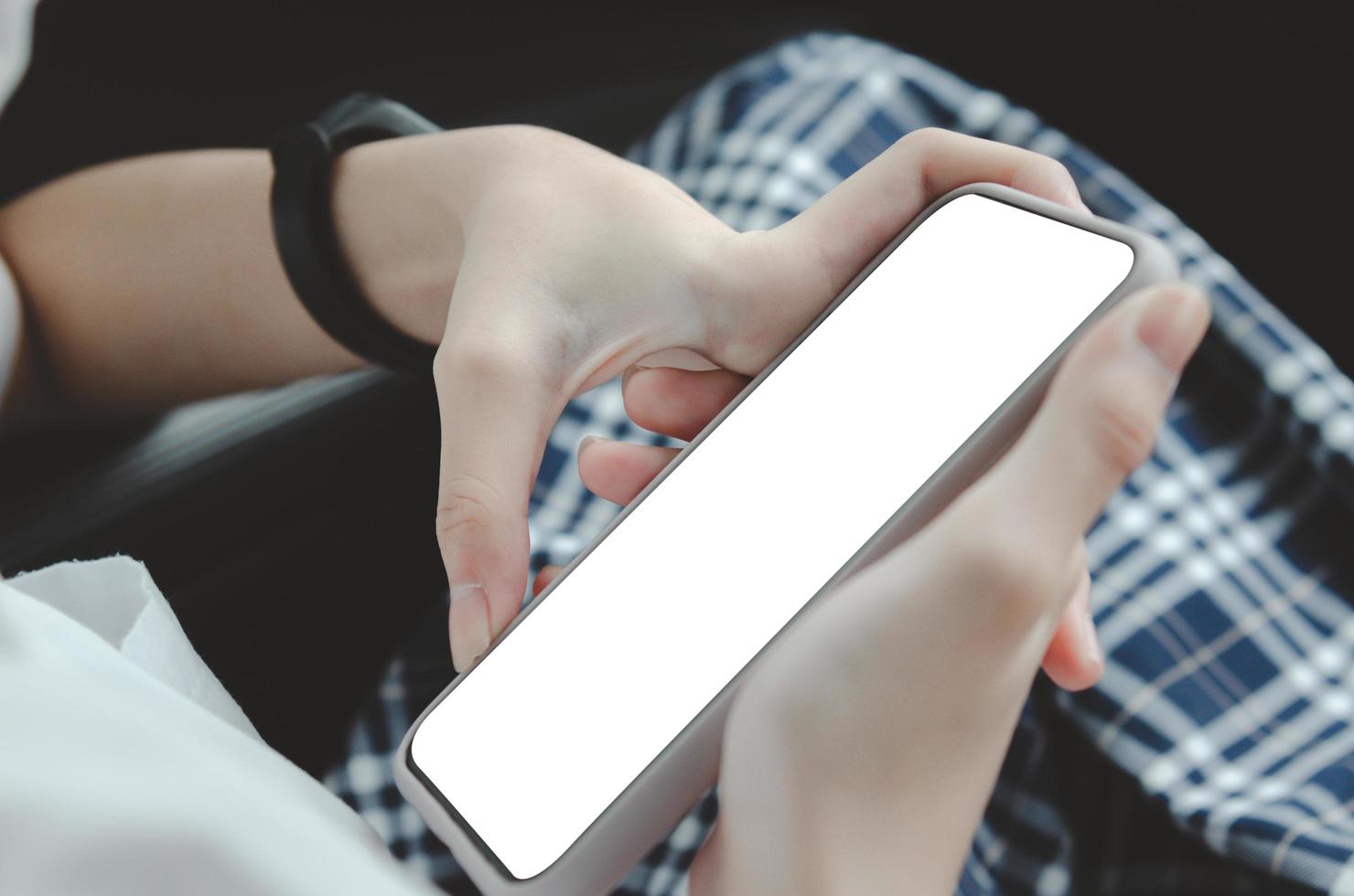 woman hand holding a mobile phone in the car cabin.Blank with white screen.Mock up smart phone interior car. photo