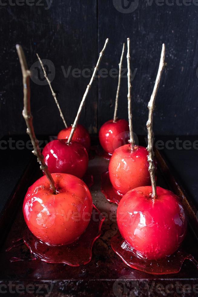 manzana de caramelo de halloween con palo de oro sobre fondo oscuro foto