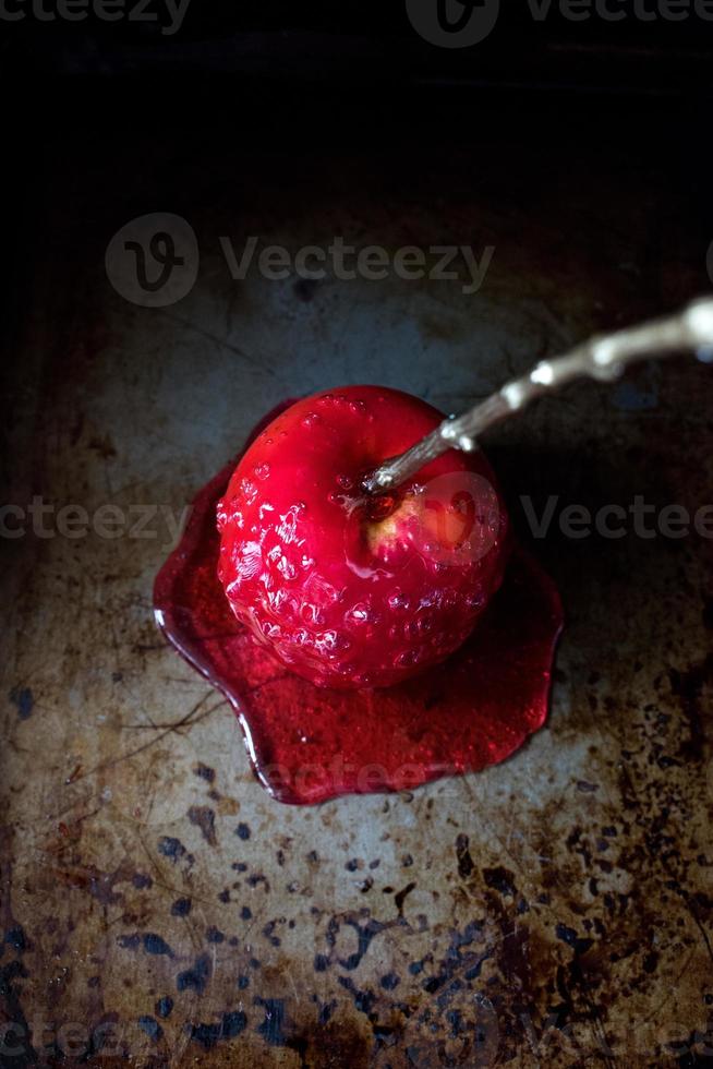 manzana de caramelo de halloween con palo de oro sobre fondo oscuro foto