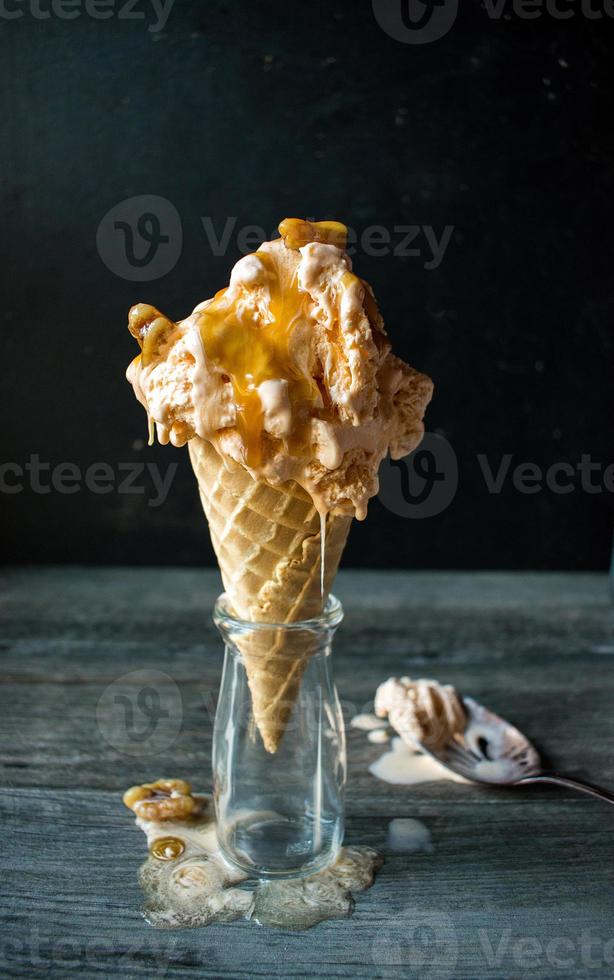 pumpkin spice ice cream with dripping caramel and walnuts in cone photo