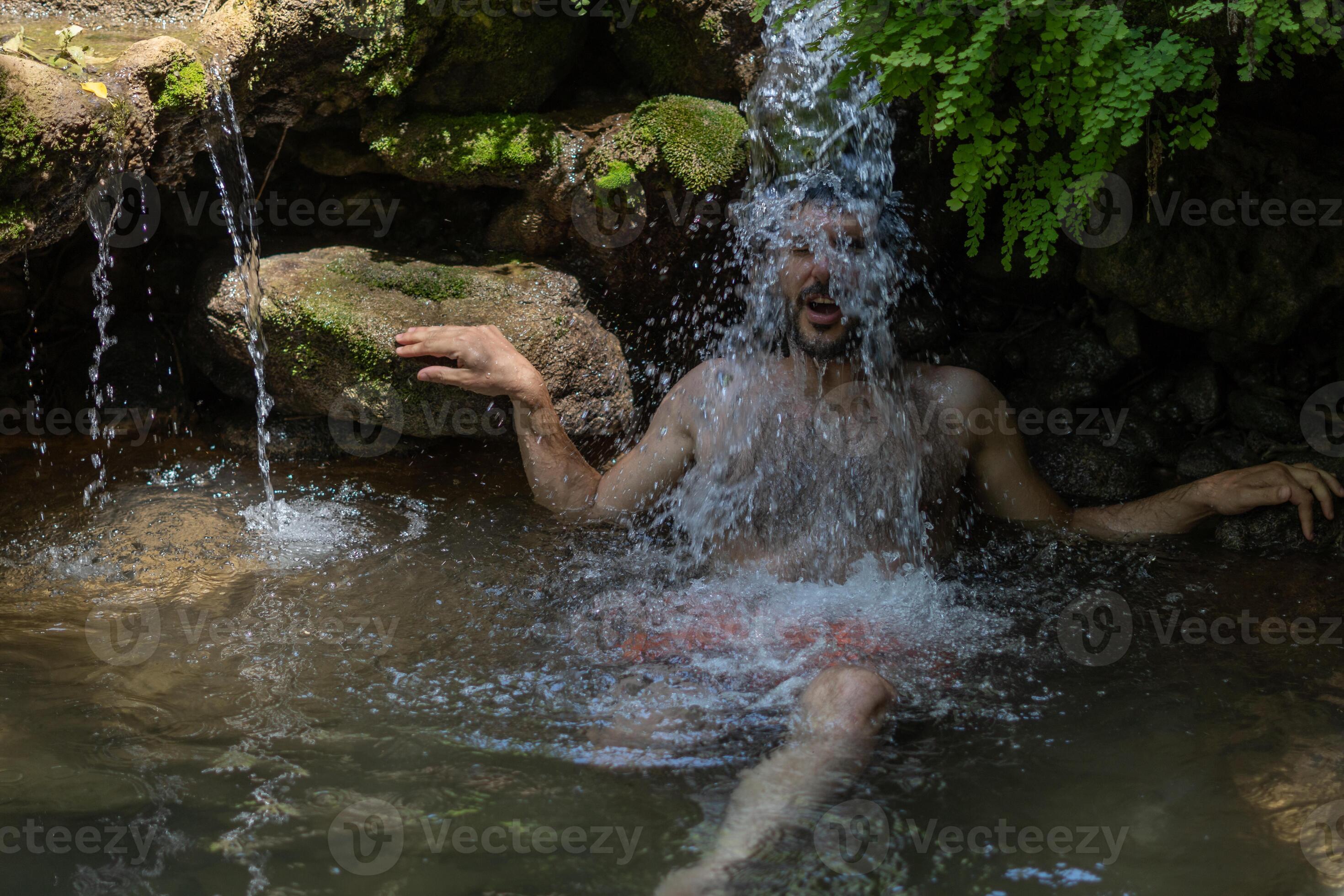 young man cooling off under a waterfall 9278423 Stock Photo at Vecteezy