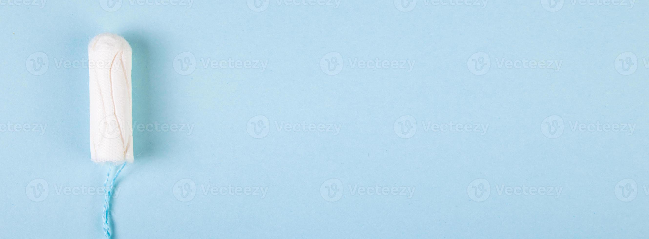 Hygienic cotton tampon on blue background. Feminine menstrual hygiene products. photo