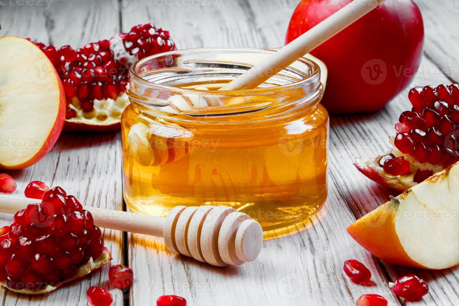 Jar with honey, apples and pomegranates on white wooden background. Happy Rosh Hashanah. Traditional symbols of Jewish New Year celebration. photo