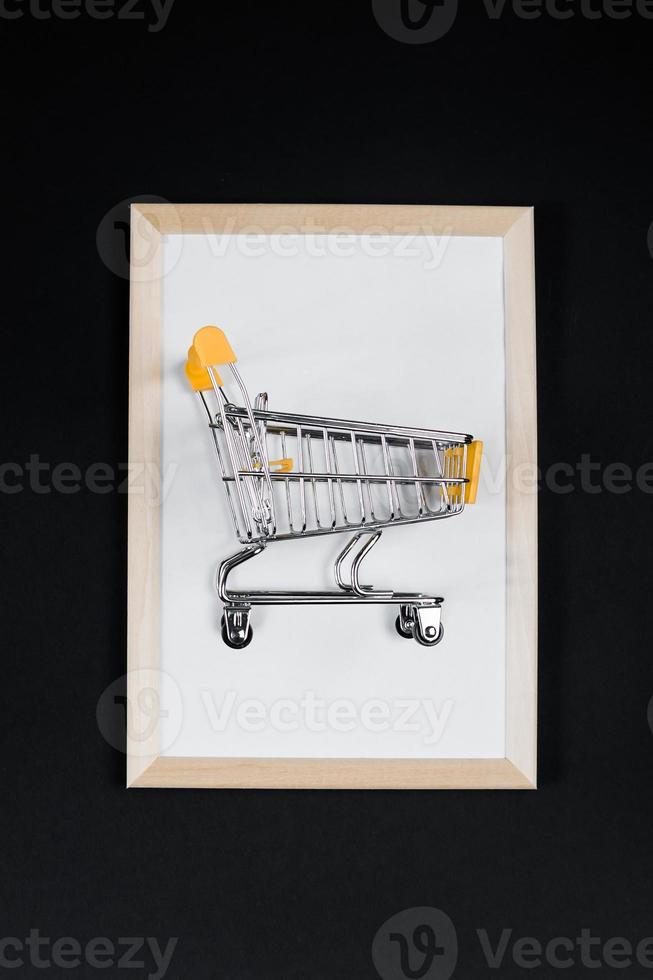 Black Friday sale. Mini shopping cart in frame on black background. photo