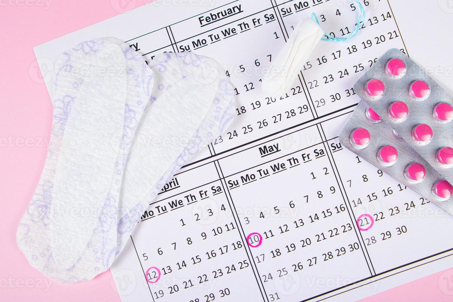 Menstruation calendar. Sanitary pads, tampons, pills on pink background. photo