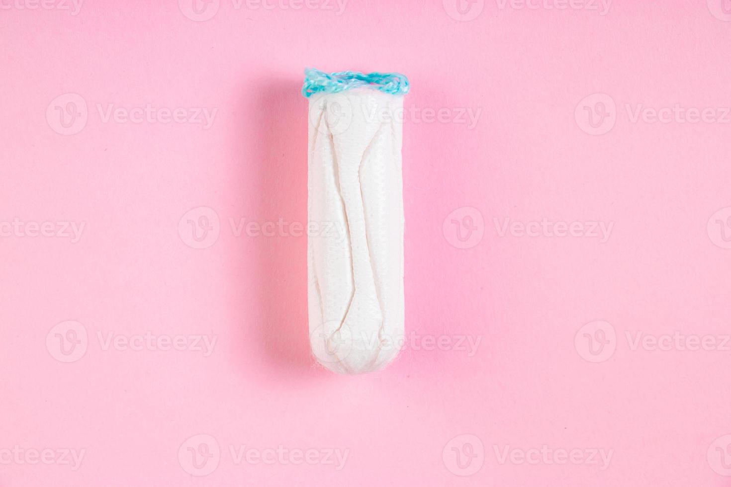 Hygienic cotton tampon on pink background. Feminine menstrual hygiene product. photo