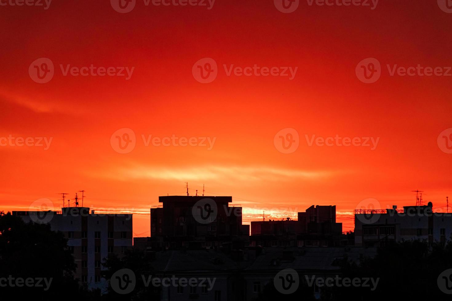 Silhouette of the city at sunset. Sun is rising over tall buildings. photo