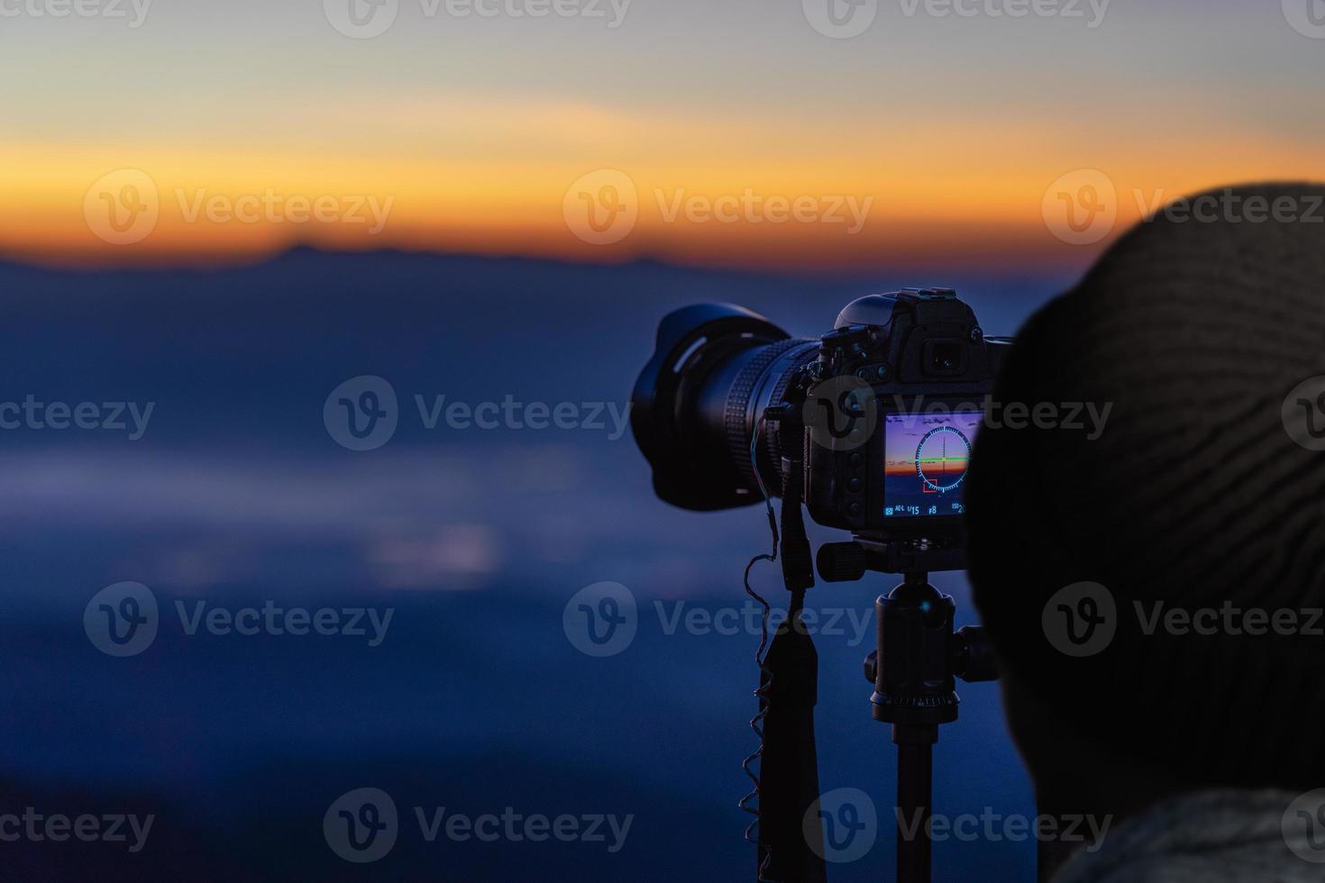 fotógrafo viajero tomando fotos del paisaje montañoso al amanecer.