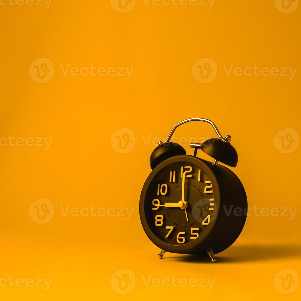 Black alarm clock on yellow background. photo