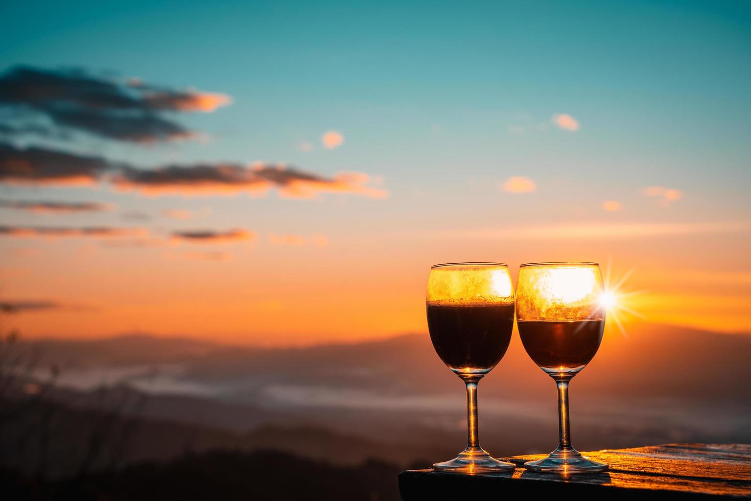 Red wine glass with the sunrise overlooking the mountains in northern of Thailand. photo