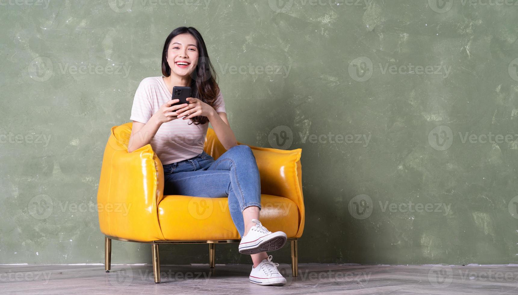 Image of beautiful young Asian woman sitting on yellow armchair photo