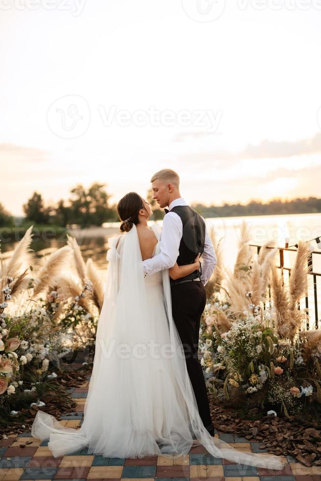 novia y novio contra el telón de fondo de una puesta de sol amarilla foto