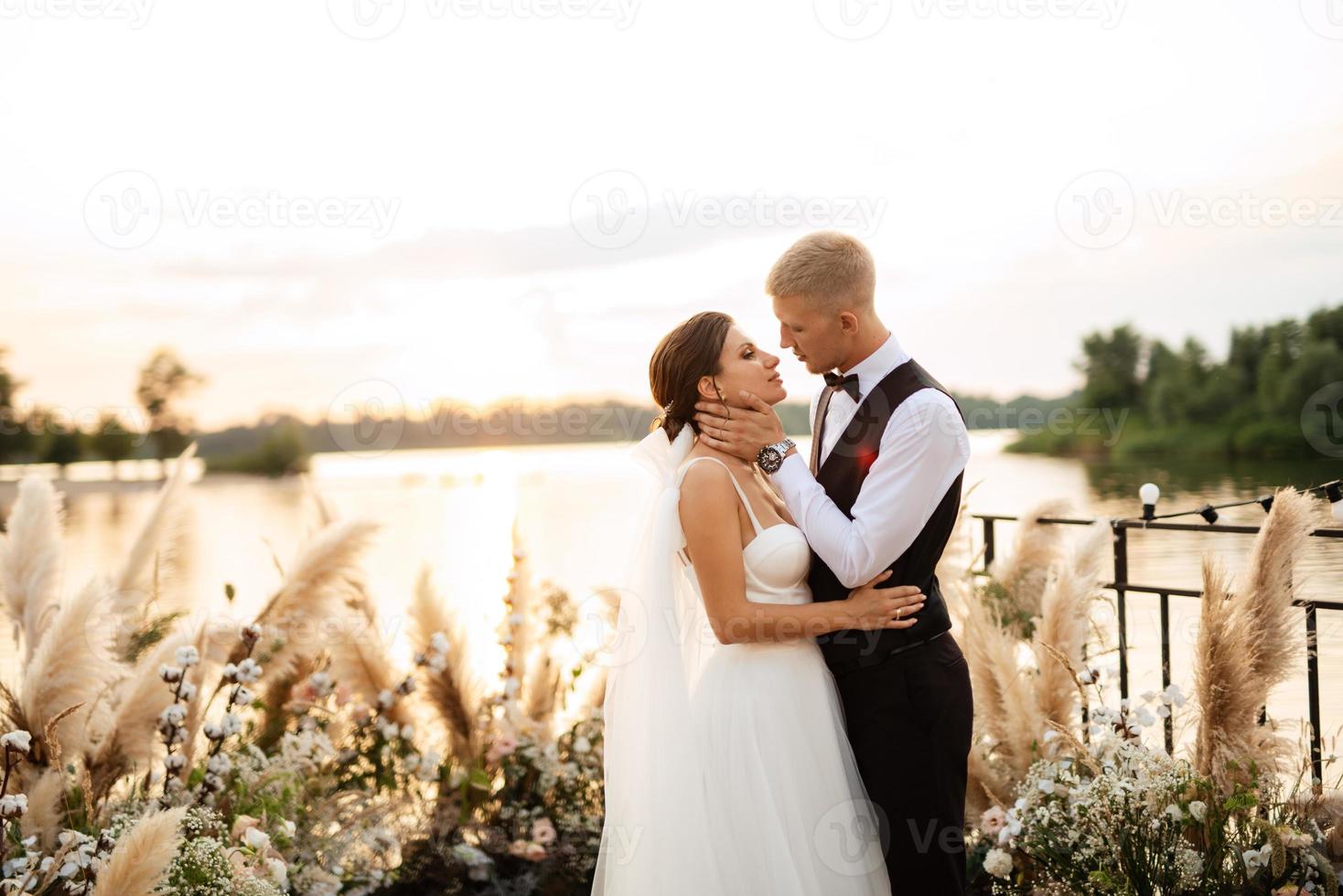 novia y novio contra el telón de fondo de una puesta de sol amarilla foto