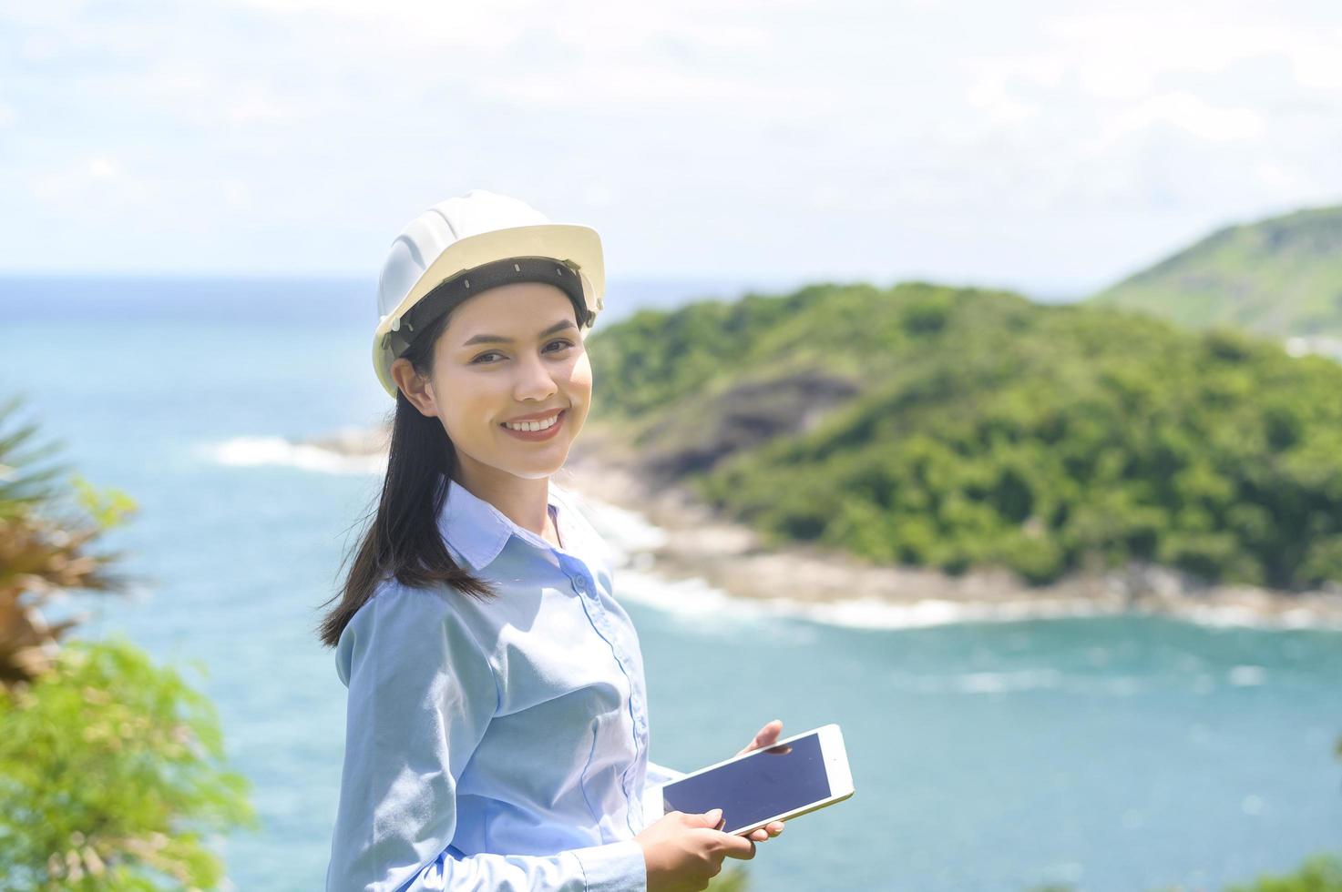 Female engineer working on the seaside wearing a protective helmet photo