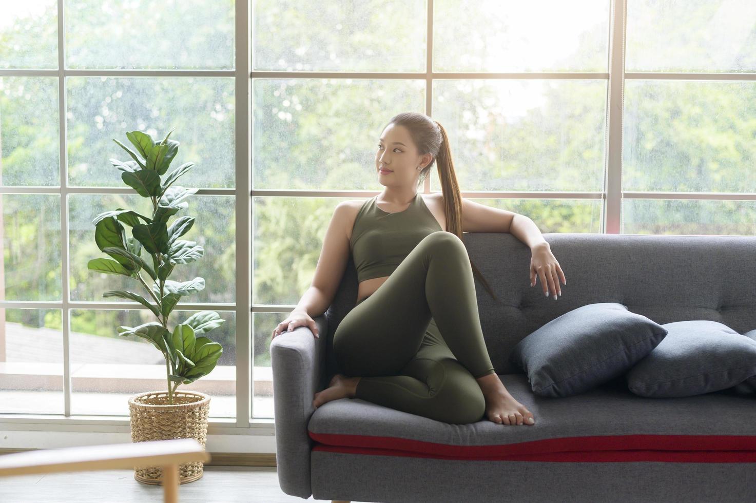 fit beautiful asain woman in sportswear sitting and relaxing on sofa after workout, health and exercise concept photo