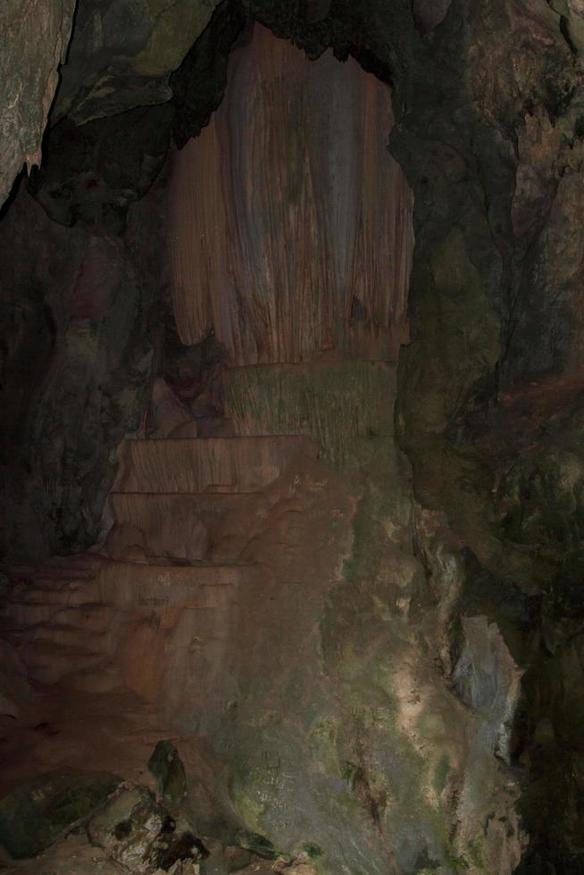 piedra caliza de granito en la cueva, pero la luz del sol brilla intensamente, mostrando las curvas y formas cóncavas de las rocas naturalmente hermosas de estalagmitas y estalactitas. foto