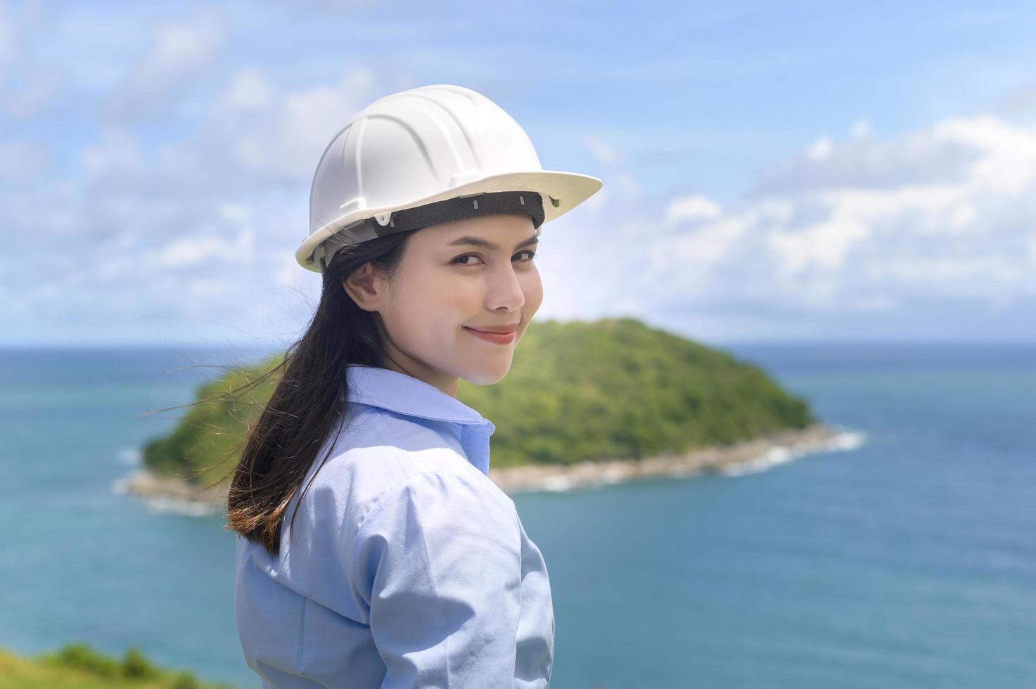mujer ingeniera trabajando en la playa con un casco protector foto