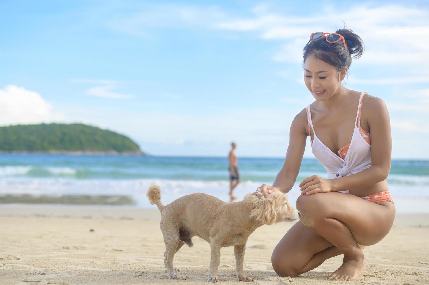 woman in Bikini with dog enjoying and relaxing on the beach,  Summer, vacation, holidays photo