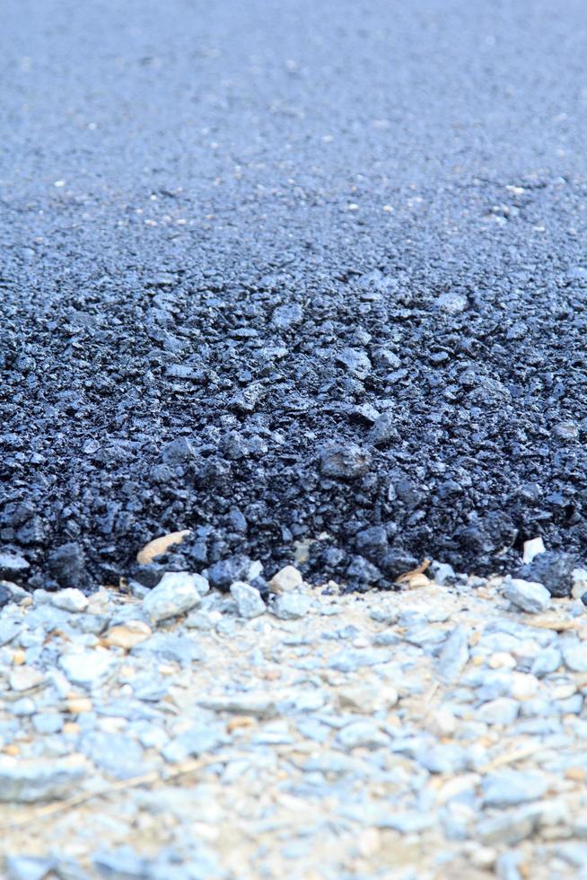 la superficie de la carretera de asfalto en construcción tiene juntas de grava, con un fondo negro y gris como imagen vertical y horizontal. foto