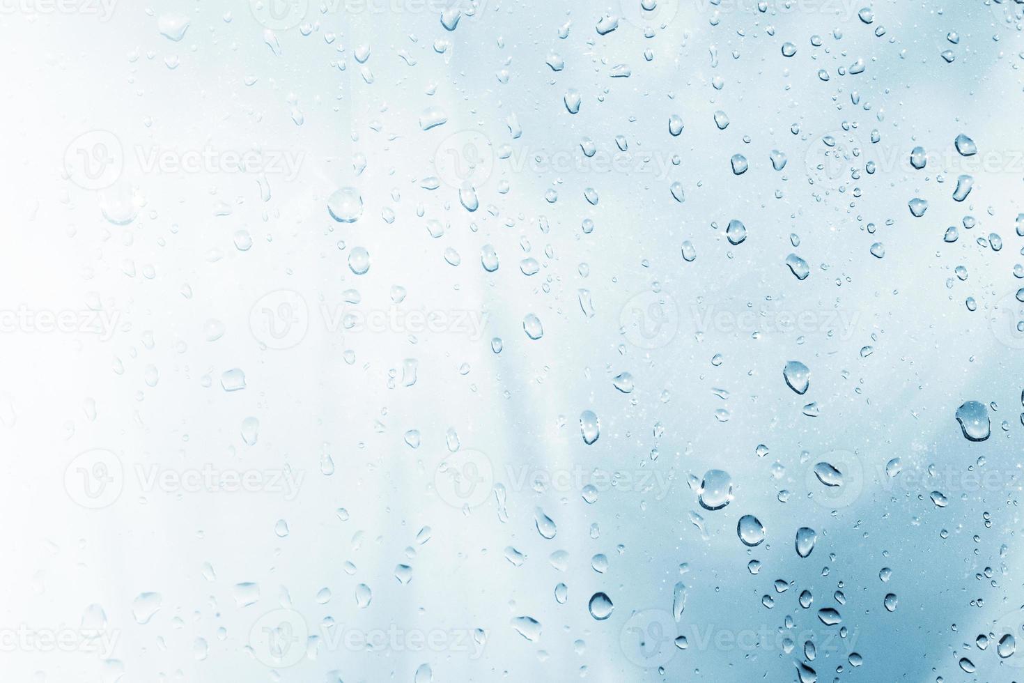 Raindrops on window glasses surface with cloudy background . photo