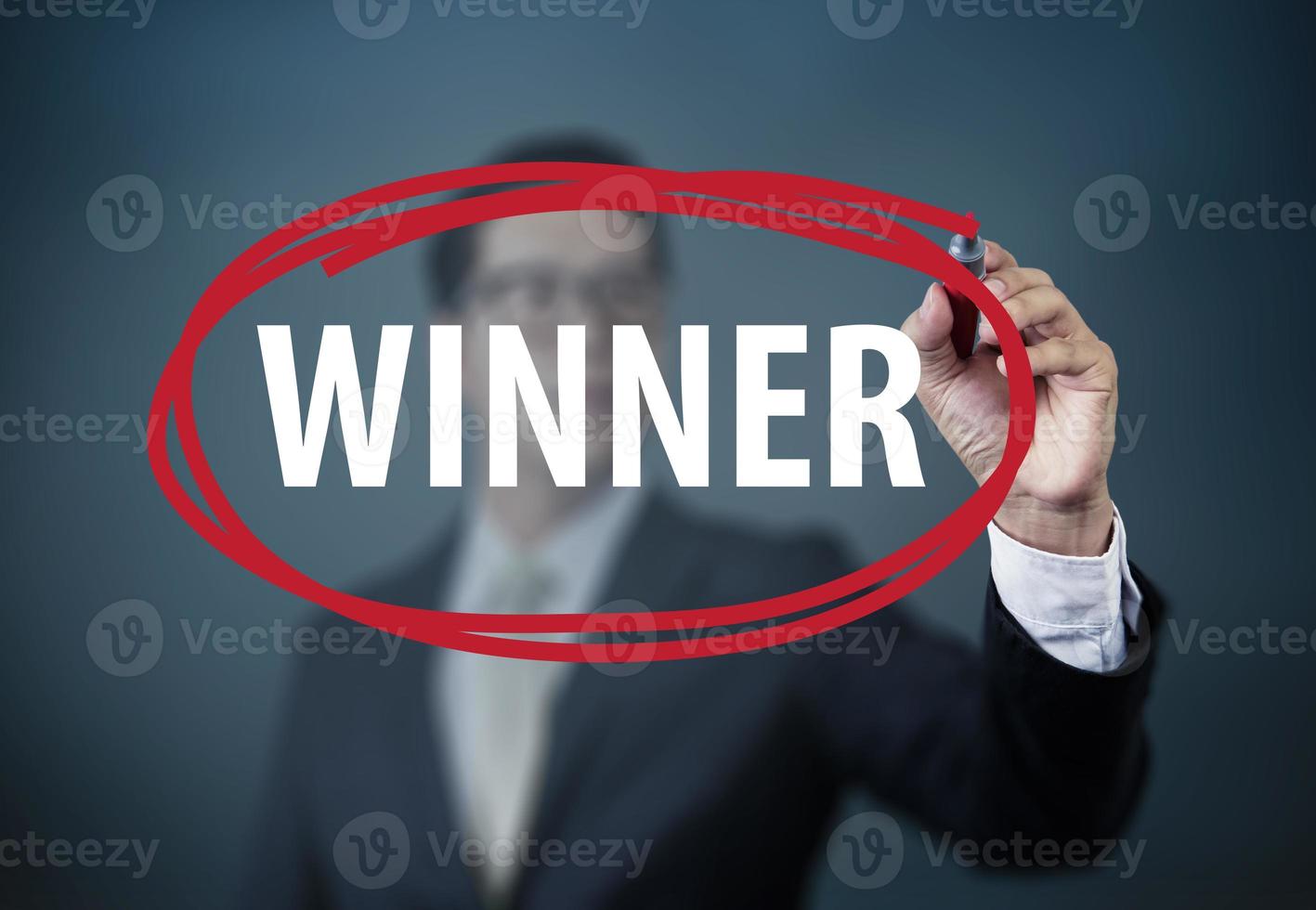 Businessman hand writing WINNER with red marker on transparent board, new business concept, studio shot photo