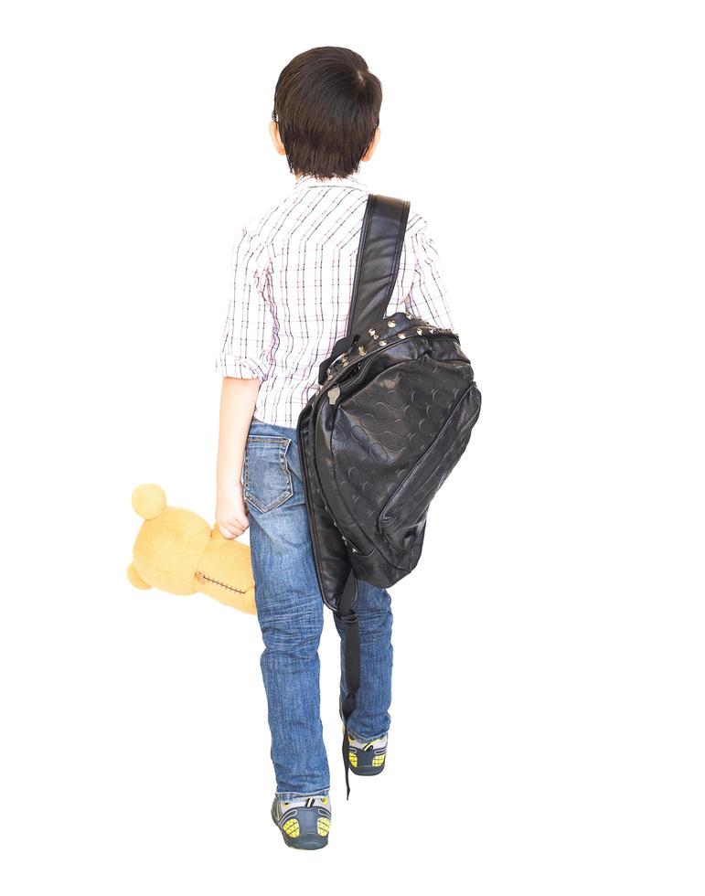 un niño asiático de siete años con una bolsa está listo para ir a la escuela aislado en blanco foto